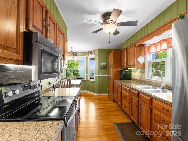 2981 Heath Peak Rd, Waynesville, NC 28785 - kitchen with appliances with stainless steel finishes, light wood-style floors, brown cabinets, a ceiling fan, and wooden walls
