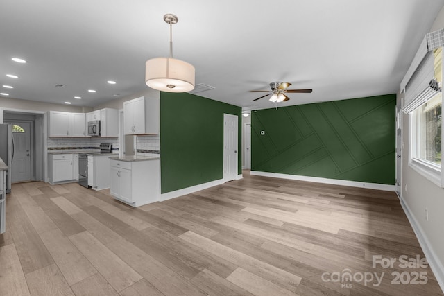 5008 Unaka Ave, Charlotte, NC 28205 - kitchen with stainless steel appliances, open floor plan, a ceiling fan, light wood-type flooring, and white cabinetry