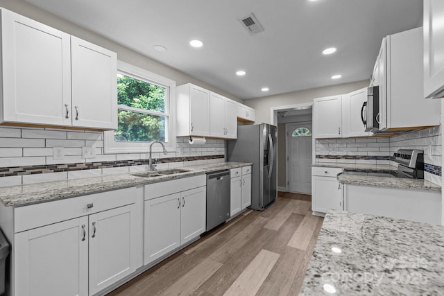 5008 Unaka Ave, Charlotte, NC 28205 - kitchen featuring appliances with stainless steel finishes, white cabinetry, light stone counters, light wood-style flooring, and backsplash
