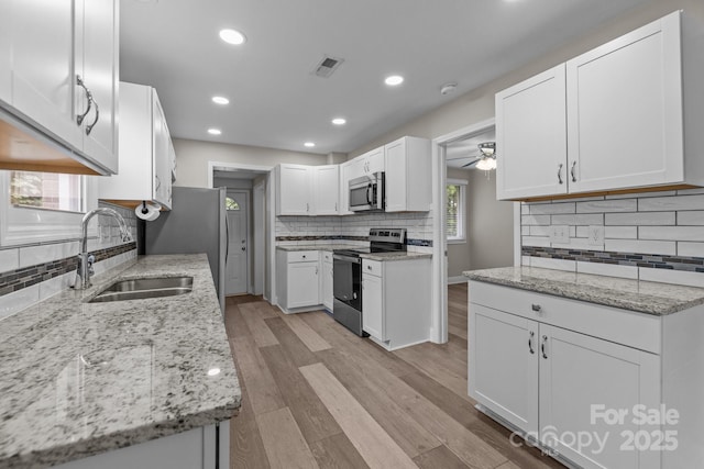 5008 Unaka Ave, Charlotte, NC 28205 - kitchen featuring stainless steel appliances, tasteful backsplash, white cabinets, light stone counters, and ceiling fan