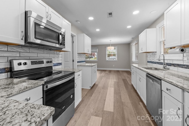 5008 Unaka Ave, Charlotte, NC 28205 - kitchen featuring stainless steel appliances, recessed lighting, white cabinets, decorative backsplash, and light wood finished floors