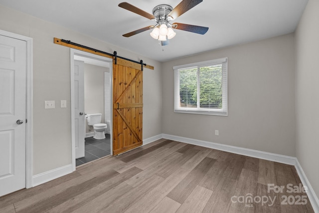 5008 Unaka Ave, Charlotte, NC 28205 - unfurnished bedroom with a barn door, wood finished floors, ensuite bathroom, and ceiling fan