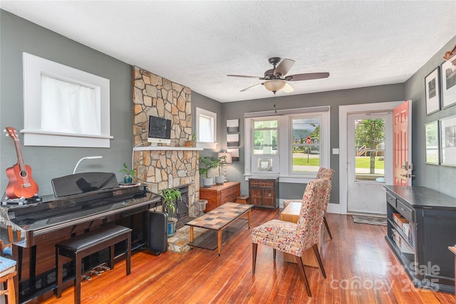 10 Poplar St, Waynesville, NC 28786 - sitting room with a textured ceiling, wood finished floors, healthy amount of natural light, ceiling fan, and a fireplace