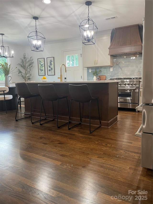 5840 Charing Pl, Charlotte, NC 28211 - kitchen featuring custom exhaust hood, high end range, a chandelier, a kitchen breakfast bar, and tasteful backsplash
