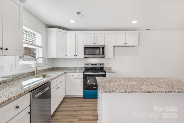 81 Kirk St, Salisbury, NC 28144 - kitchen featuring appliances with stainless steel finishes, a sink, light wood-style flooring, white cabinetry, and recessed lighting