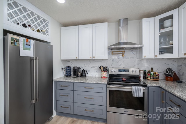 1256 Canseco Ln, Hickory, NC 28602 - kitchen featuring appliances with stainless steel finishes, wall chimney range hood, white cabinetry, glass insert cabinets, and decorative backsplash