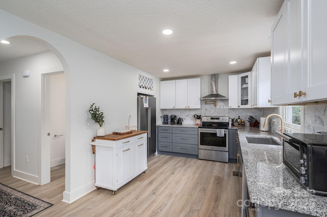 1256 Canseco Ln, Hickory, NC 28602 - kitchen with appliances with stainless steel finishes, wall chimney range hood, light wood-type flooring, arched walkways, and tasteful backsplash