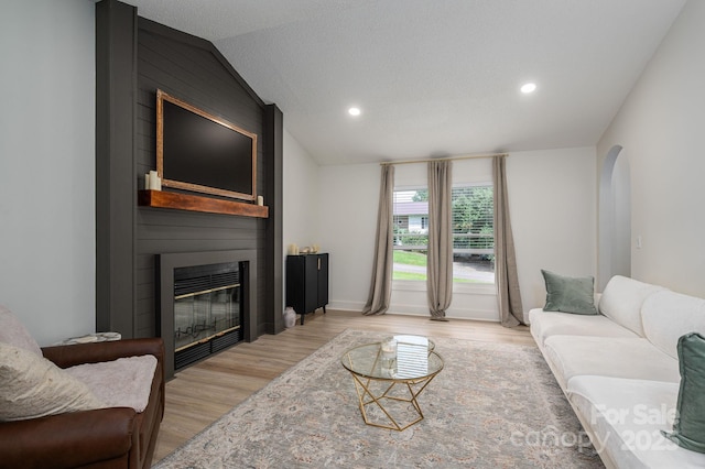 1256 Canseco Ln, Hickory, NC 28602 - living room featuring light wood finished floors, a fireplace, vaulted ceiling, arched walkways, and recessed lighting