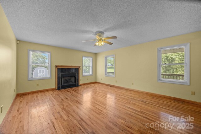449 Concord Rd, Fletcher, NC 28732 - unfurnished living room with healthy amount of natural light, light wood-style floors, a ceiling fan, a fireplace, and a textured ceiling