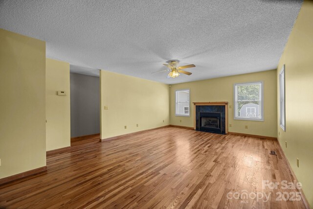 449 Concord Rd, Fletcher, NC 28732 - unfurnished living room with wood finished floors, ceiling fan, a textured ceiling, a tile fireplace, and baseboards