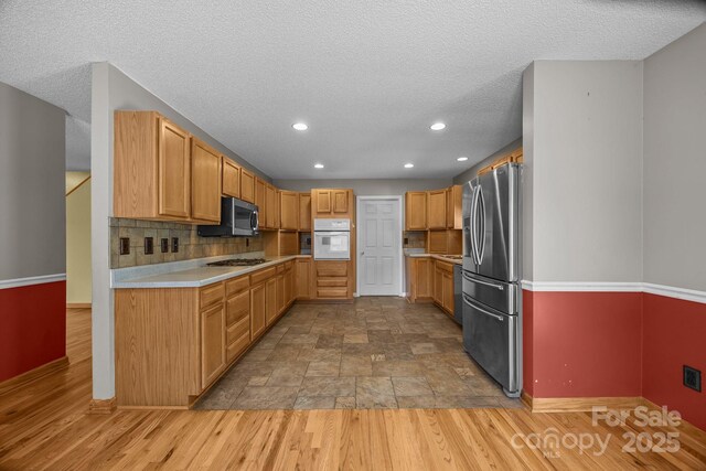 449 Concord Rd, Fletcher, NC 28732 - kitchen featuring appliances with stainless steel finishes, baseboards, light countertops, a textured ceiling, and backsplash