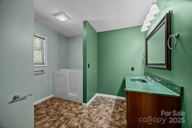 449 Concord Rd, Fletcher, NC 28732 - full bathroom with vanity, baseboards, a textured ceiling, stone finish flooring, and a garden tub