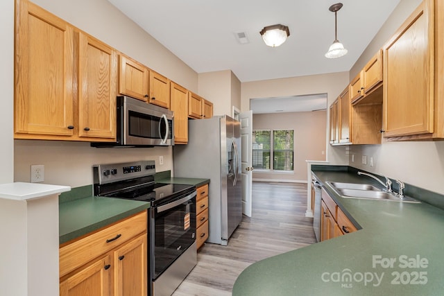 5322 Jocelyn Ln, Charlotte, NC 28269 - kitchen featuring appliances with stainless steel finishes, light wood-type flooring, a sink, dark countertops, and hanging light fixtures