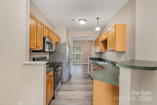 5322 Jocelyn Ln, Charlotte, NC 28269 - kitchen with stainless steel appliances, light wood-style flooring, a sink, a peninsula, and dark countertops