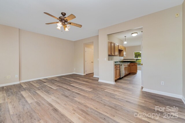 5322 Jocelyn Ln, Charlotte, NC 28269 - unfurnished living room featuring light wood-type flooring, ceiling fan, and baseboards