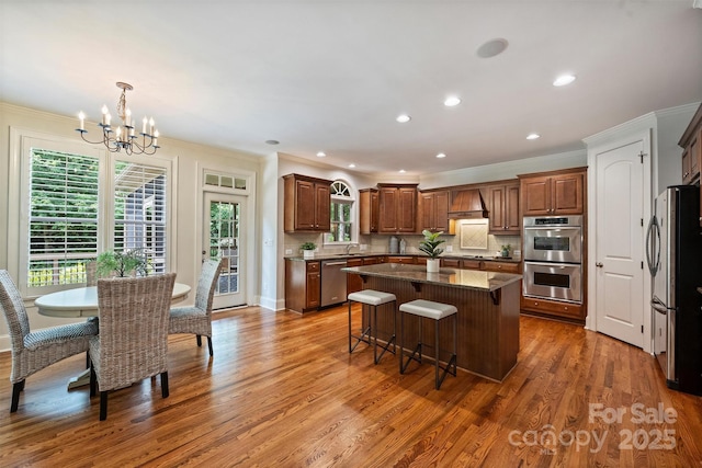 7319 Stonehaven Dr, Waxhaw, NC 28173 - kitchen with stainless steel appliances, custom exhaust hood, ornamental molding, a kitchen island, and plenty of natural light