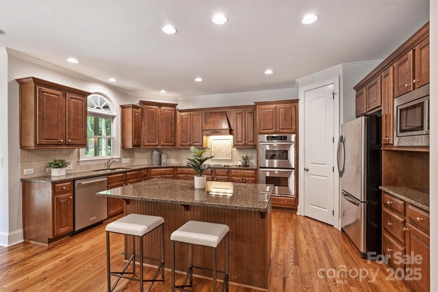 7319 Stonehaven Dr, Waxhaw, NC 28173 - kitchen with stainless steel appliances, a sink, a center island, a breakfast bar area, and crown molding