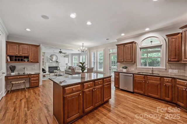 7319 Stonehaven Dr, Waxhaw, NC 28173 - kitchen with dishwasher, a sink, a glass covered fireplace, ornamental molding, and light wood finished floors