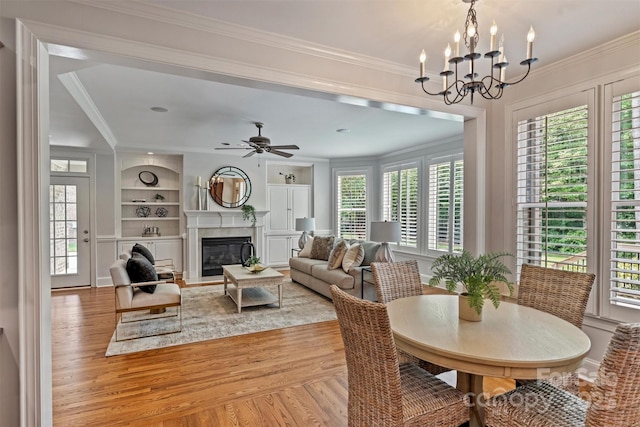 7319 Stonehaven Dr, Waxhaw, NC 28173 - dining room featuring light wood-style flooring, crown molding, built in features, a chandelier, and a fireplace