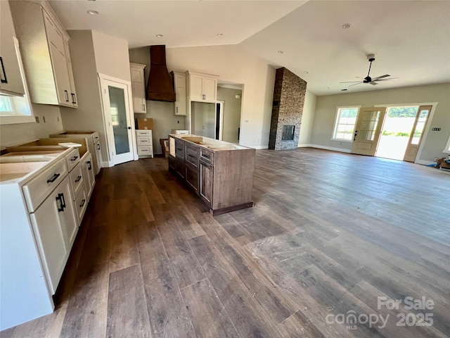 3000 Paul Payne Store Rd, Taylorsville, NC 28681 - kitchen featuring custom exhaust hood, a kitchen island, a ceiling fan, a fireplace, and dark wood-style flooring