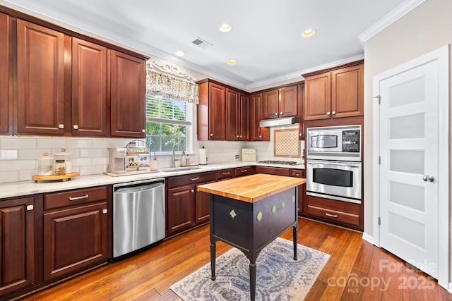622 Lorain Ave NW, Concord, NC 28027 - kitchen with appliances with stainless steel finishes, ornamental molding, under cabinet range hood, wood counters, and backsplash