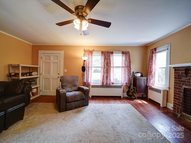 1614 Linwood Rd, Gaston, NC 28052 - living room featuring radiator, wood finished floors, crown molding, a brick fireplace, and a ceiling fan