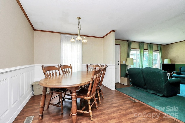 4104 Pebblebrook Cir SW, Concord, NC 28027 - dining area with ornamental molding, wood finished floors, a decorative wall, and wainscoting