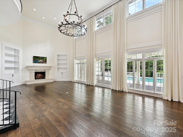 4300 Cameron Oaks Dr, Charlotte, NC 28211 - unfurnished living room with a high ceiling, built in features, a chandelier, a lit fireplace, and ornamental molding