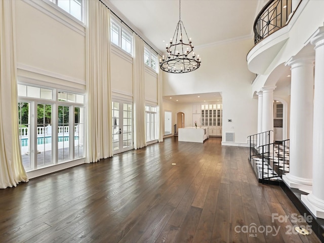 4300 Cameron Oaks Dr, Charlotte, NC 28211 - living area with a towering ceiling, a chandelier, arched walkways, dark wood-type flooring, and decorative columns