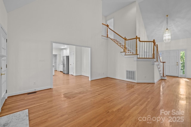 765 Portpatrick Pl, Fort Mill, SC 29708 - unfurnished living room featuring a high ceiling, stairway, light wood finished floors, baseboards, and a chandelier
