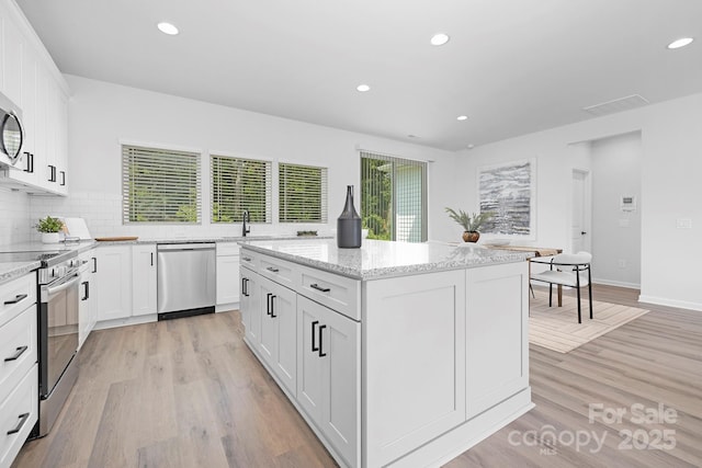 1312 W Monroe Rd, Salisbury, NC 28144 - kitchen with appliances with stainless steel finishes, light wood-type flooring, a center island, recessed lighting, and white cabinetry