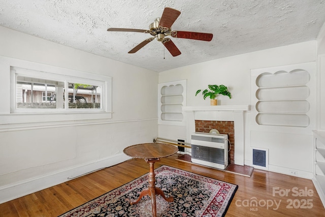 113 4th St, Black Mountain, NC 28711 - sitting room with a textured ceiling, wood finished floors, a fireplace with flush hearth, heating unit, and ceiling fan