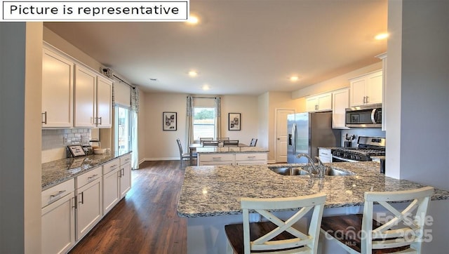 1369 Secrest Commons Dr, Monroe, NC 28112 - kitchen featuring appliances with stainless steel finishes, a sink, a center island, dark wood-style flooring, and white cabinetry