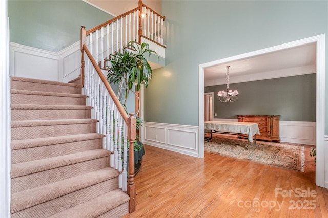 8219 Beardsley Dr, Charlotte, NC 28269 - staircase with wainscoting, a decorative wall, wood finished floors, a chandelier, and ornamental molding