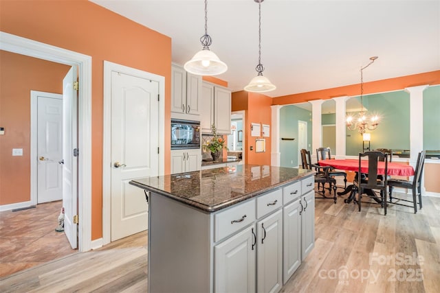 8219 Beardsley Dr, Charlotte, NC 28269 - kitchen with a center island, ornate columns, light wood finished floors, black microwave, and hanging light fixtures