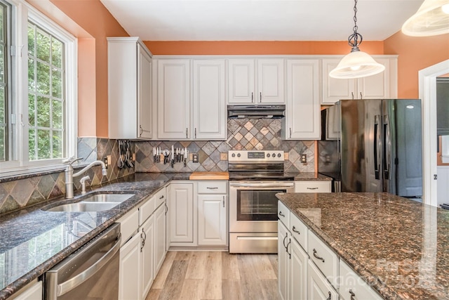 8219 Beardsley Dr, Charlotte, NC 28269 - kitchen featuring appliances with stainless steel finishes, a sink, under cabinet range hood, decorative light fixtures, and white cabinetry