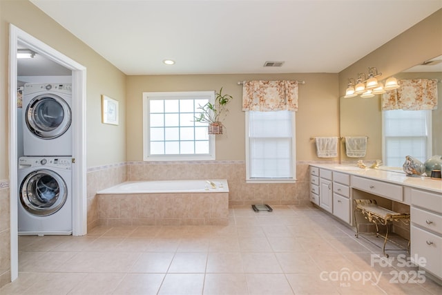 8219 Beardsley Dr, Charlotte, NC 28269 - bathroom with stacked washing machine and dryer, tile patterned floors, vanity, a garden tub, and wainscoting