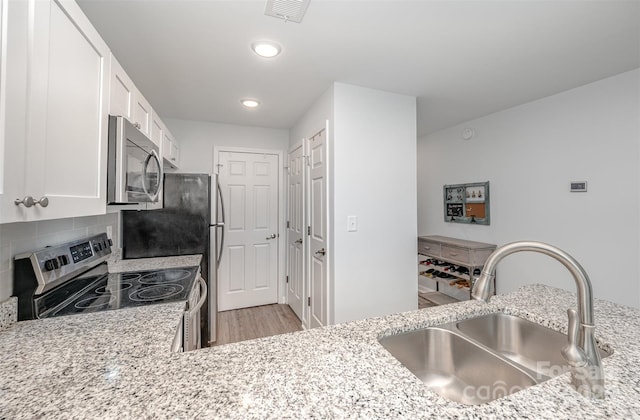 18741 Nautical Dr Unit 205, Cornelius, NC 28031 - kitchen featuring a sink, stainless steel appliances, white cabinets, light stone countertops, and recessed lighting