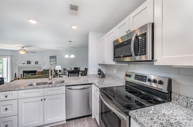 18741 Nautical Dr Unit 205, Cornelius, NC 28031 - kitchen featuring appliances with stainless steel finishes, a sink, a tile fireplace, white cabinets, and ceiling fan