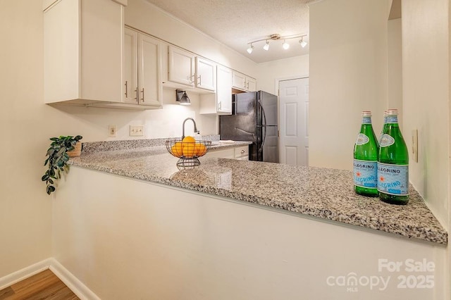 118 Colony Dr, Arden, NC 28704 - kitchen featuring freestanding refrigerator, light stone countertops, wood finished floors, white cabinetry, and a textured ceiling
