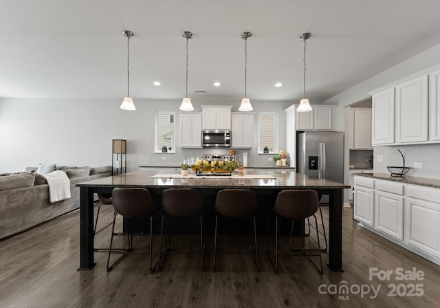 204 Fesperman Cir, Troutman, NC 28166 - kitchen with appliances with stainless steel finishes, a center island, a breakfast bar area, white cabinetry, and dark wood-type flooring