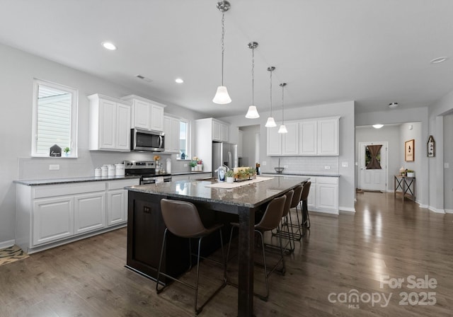 204 Fesperman Cir, Troutman, NC 28166 - kitchen featuring stainless steel appliances, a center island, tasteful backsplash, a breakfast bar area, and dark wood-type flooring