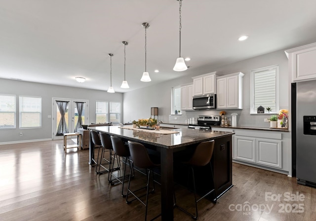 204 Fesperman Cir, Troutman, NC 28166 - kitchen featuring stainless steel appliances, a breakfast bar area, decorative backsplash, a kitchen island, and dark wood finished floors