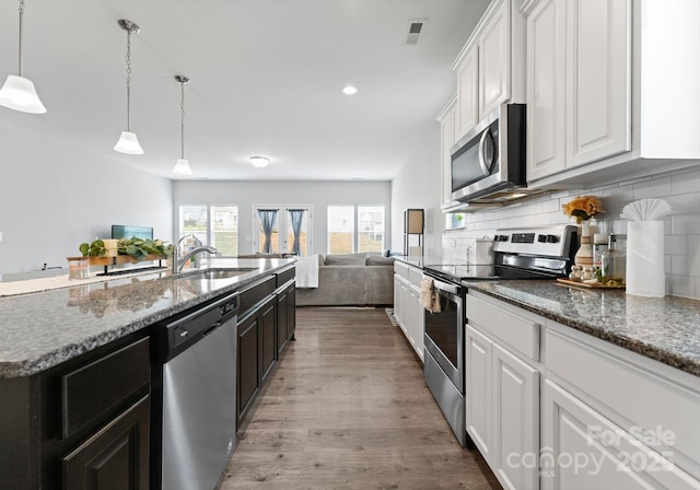 204 Fesperman Cir, Troutman, NC 28166 - kitchen with appliances with stainless steel finishes, open floor plan, white cabinets, wood finished floors, and recessed lighting