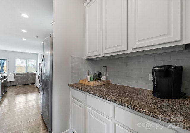 204 Fesperman Cir, Troutman, NC 28166 - kitchen with freestanding refrigerator, white cabinetry, open floor plan, dark stone counters, and backsplash