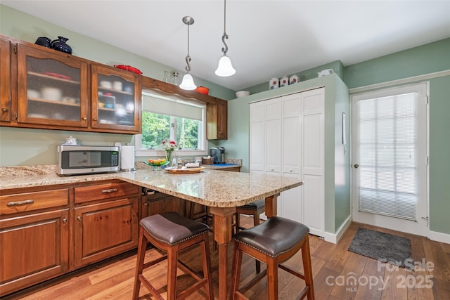 58 Campbell Creek Rd, Maggie Valley, NC 28751 - kitchen with stainless steel microwave, a breakfast bar, light wood finished floors, brown cabinets, and hanging light fixtures
