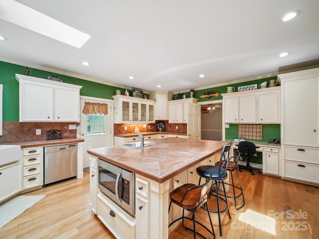 2442 Singleton Pt Unit 67, Liberty Hill, SC 29074 - kitchen with appliances with stainless steel finishes, a breakfast bar, white cabinets, tasteful backsplash, and ornamental molding