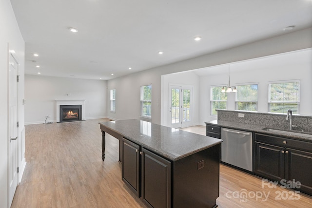 207 Welcombe St, Mooresville, NC 28115 - kitchen with stainless steel dishwasher, a sink, light wood finished floors, a center island, and a fireplace with flush hearth