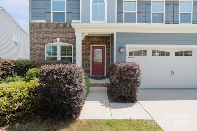 207 Welcombe St, Mooresville, NC 28115 - doorway to property featuring brick siding, concrete driveway, and a garage