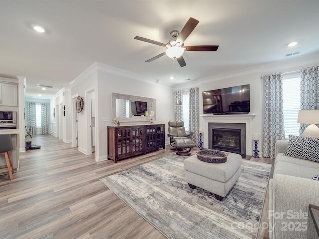 647 R L Stowe Rd, Belmont, NC 28012 - living room with ornamental molding, a ceiling fan, a glass covered fireplace, light wood finished floors, and baseboards
